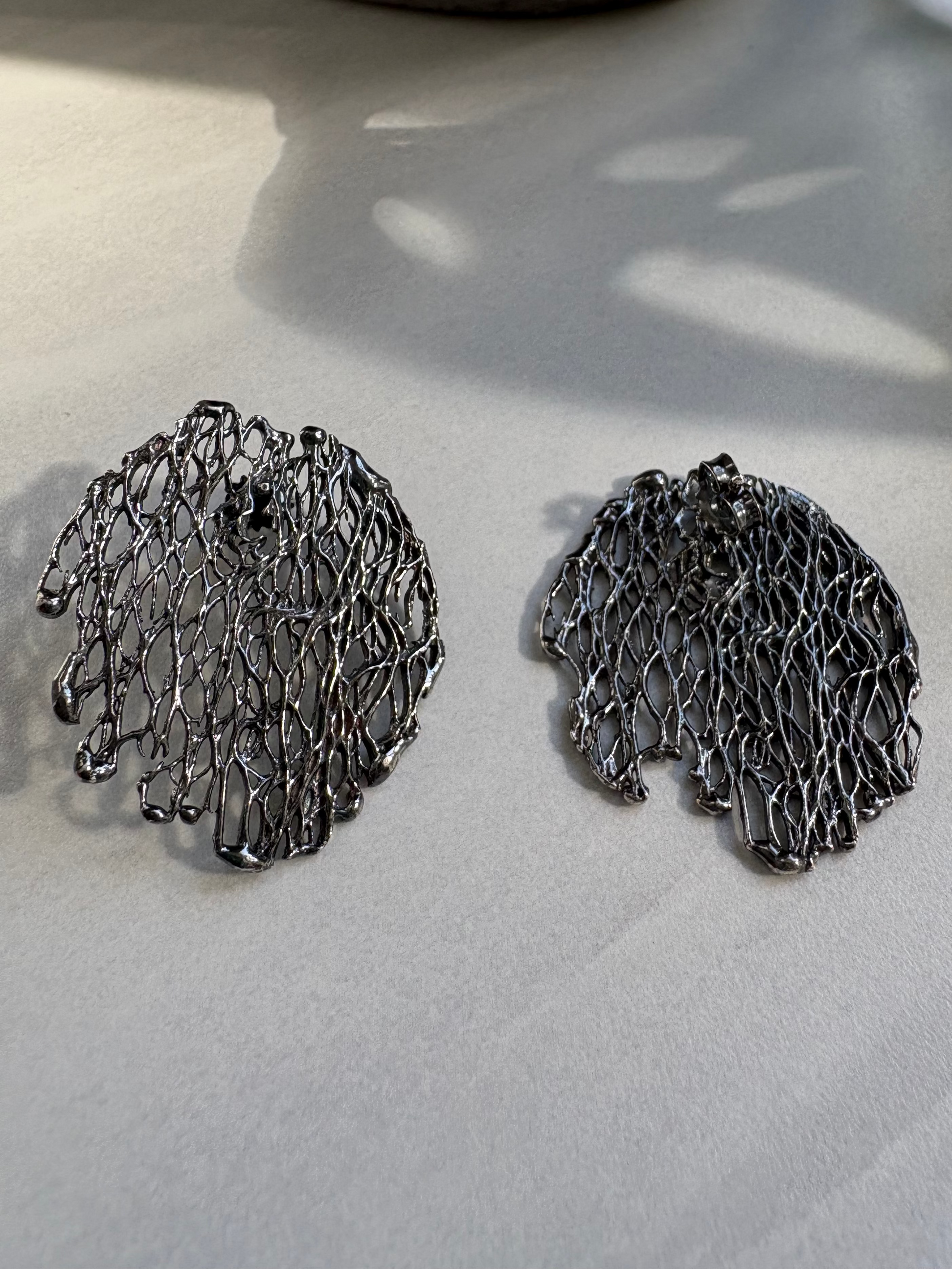 Pair of oxidised silver earrings on a light surface