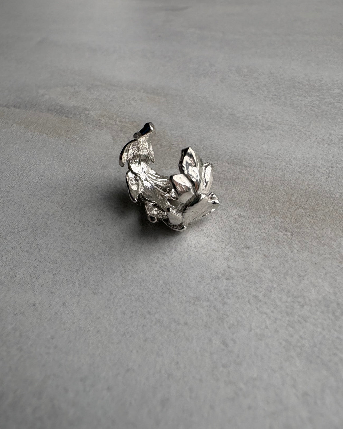 Silver leaf earcuff on a gray textured background