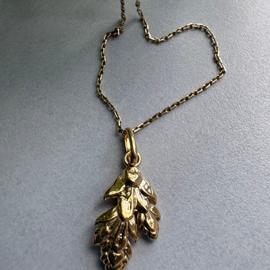 Goldplated  necklace with leaf pendant on a gray background