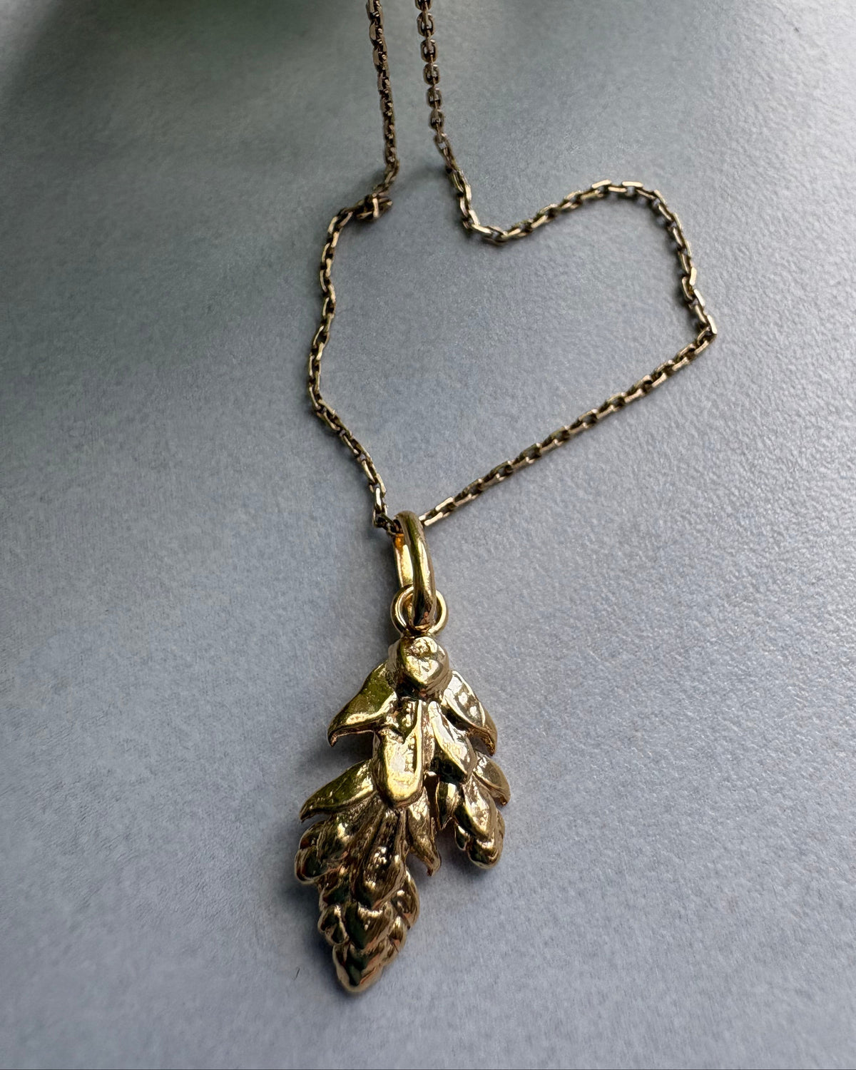 Goldplated  necklace with leaf pendant on a gray background
