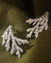 A pair of sterling silver leaf-shaped earrings displayed on a dark olive green fabric background.