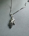 Silver leaf pendant necklace on a gray background