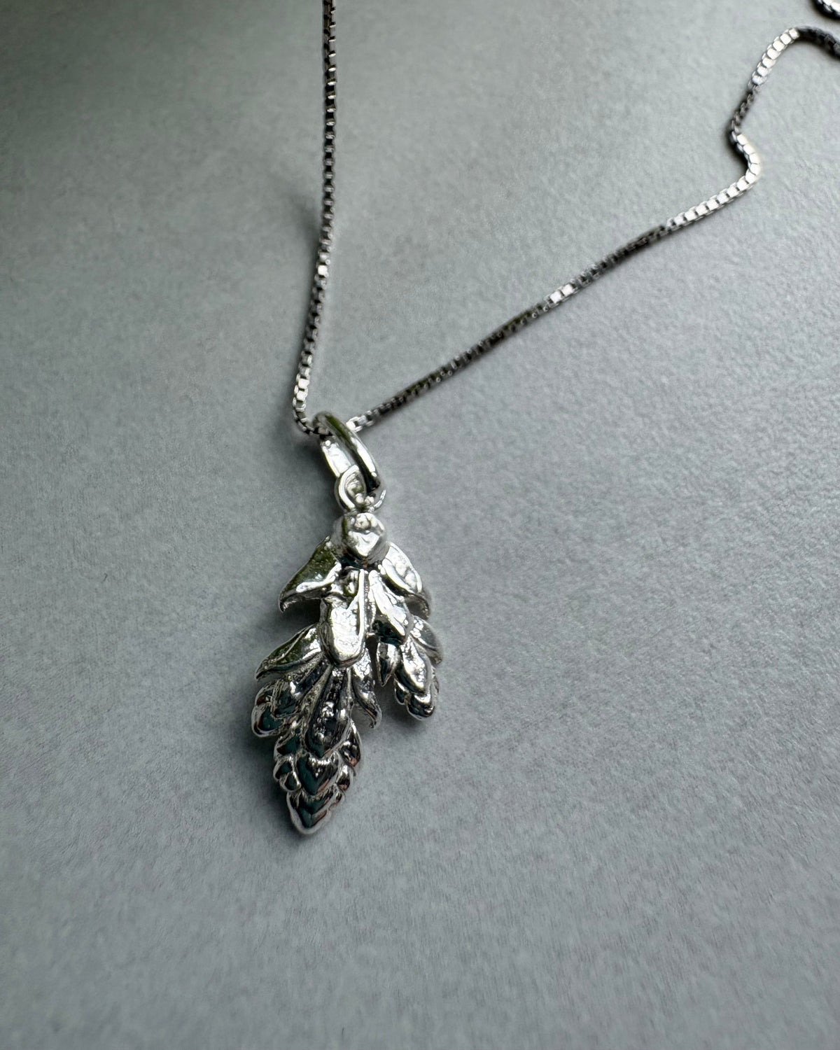 Silver leaf pendant necklace on a gray background