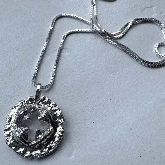 Silver necklace with a detailed pendant on a gray surface