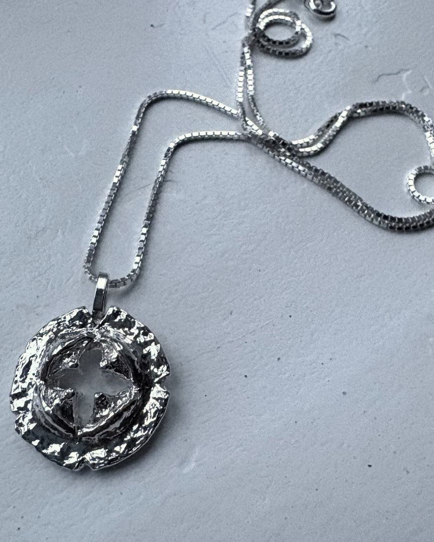 Silver necklace with a detailed pendant on a gray surface