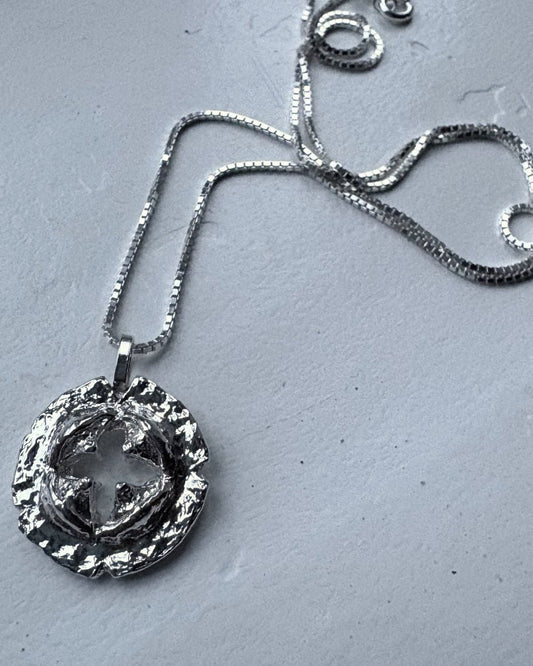 Silver necklace with a detailed pendant on a gray surface