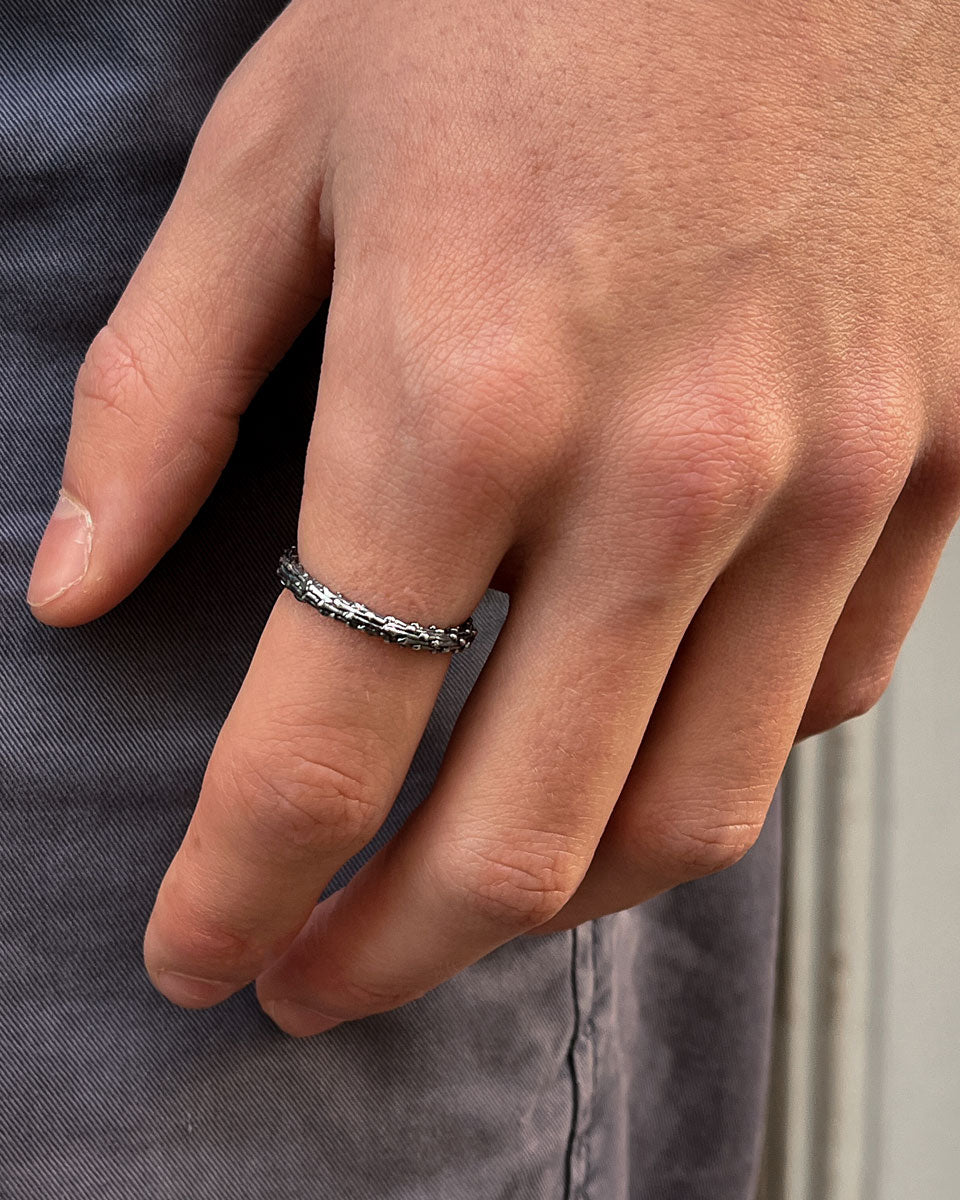 Close-up of a hand wearing a silver ring on a gray fabric background