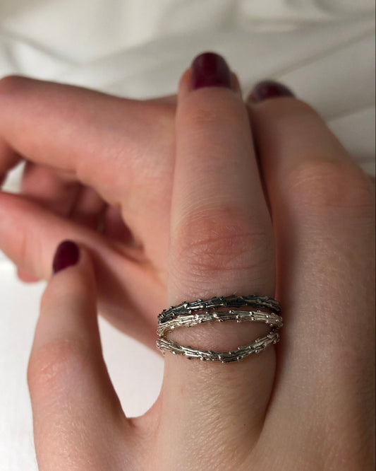 Hand wearing multiple rings with a blurred background
