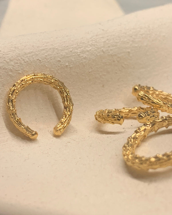 Gold hoop earcuff textured on a beige background