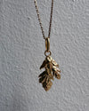 Gold necklace with leaf pendant on a gray background