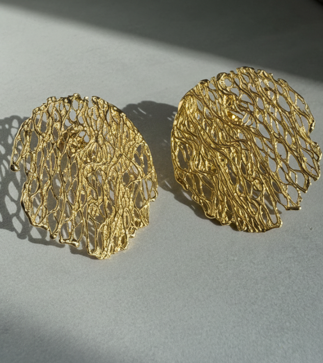 Pair of gold lace-style earrings on a light gray background