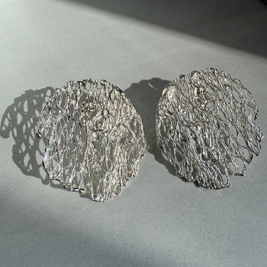 Pair of silver textured earrings on a light gray surface