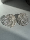 Pair of silver textured earrings on a light gray surface